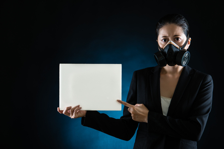 Pretty Asian business woman wearing a face mask to protect against pollution presenting blank board for text. mixed race asian chinese modelの写真素材