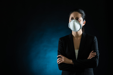 Person wearing protective mask against transmissible infectious diseases and as protection against pollution and the flu. Beautiful mixed race asian chinese modelの写真素材