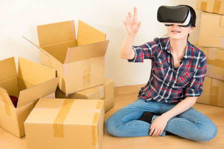 enjoys a new apartment while beautiful woman sitting on floor with VR headset device simulation. mixed race asian chinese model.の写真素材