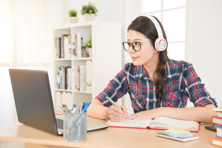 student learning on line with headphones and laptop. mixed race asian chinese model.の写真素材