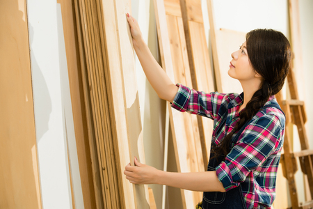 carpenter testing wood plank evenness and choosing best wood board at workshop. mixed race asian chinese model.の写真素材