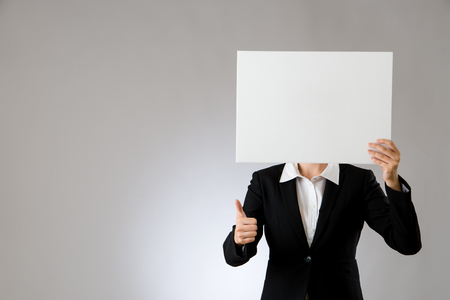 beautiful business woman thumbs up hand gesture with holding showing blank board, isolated on gray background.の写真素材