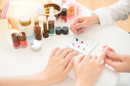 young woman with colorful nail polish coloring painting by professional manicurist using in real salon store background. beauty and fashion concept.の写真素材