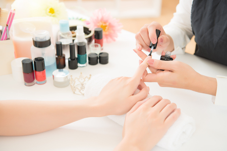 closeup of beautiful female hands applying transparent nail polish on healthy natural woman's spa background. beauty and fashion concept.の写真素材