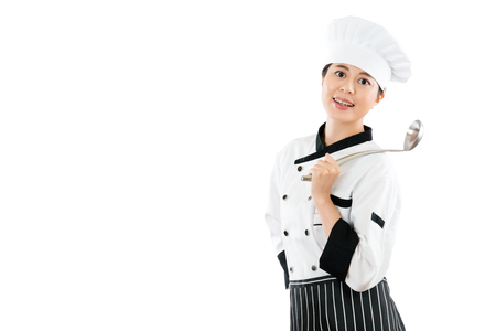 smiling restaurant chef holding a spoon on the shoulder affectionately facing the camera and showing the advertising area isolated on white background with copyspace on the blank wall.の写真素材