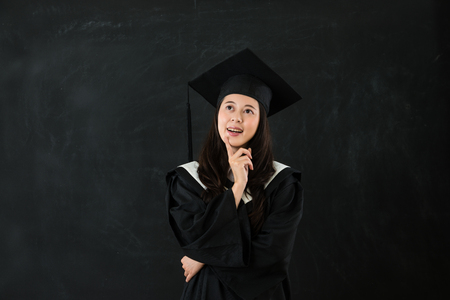 education, graduate and woman concept. isolated on blackboard with copyspace for empty. pleasantly girl smile think for future.の写真素材