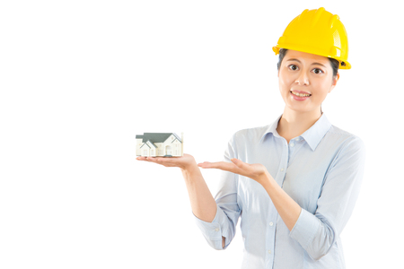beautiful asian woman holding a model house isolated on white background presenting displaying showing in the copyspace with blank area over clean wall.の写真素材