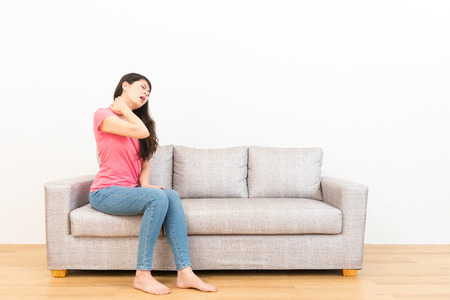 woman working fatigue everyday feeling neck pain and performed uncomfortable painful expression on sofa with wooden floor on white background.の写真素材