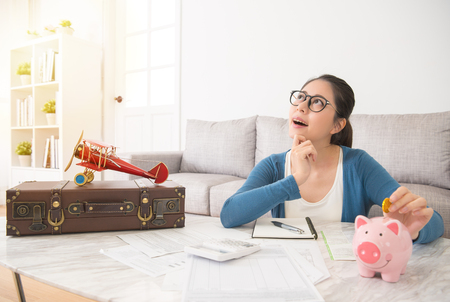 young housewife save money looking at the top imagine the picture when traveling hoping to have a foreign holiday day dreaming with lover and regularly record the expenditure at home.の写真素材