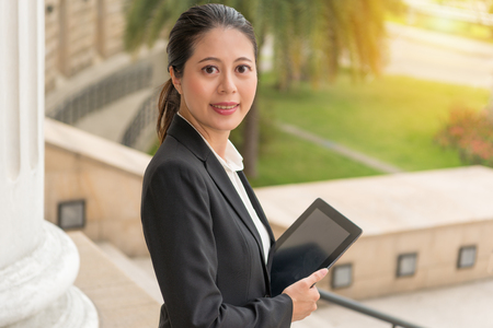 professional business woman lawyer holding technology mobile pad smile standing at court waiting for legal advice to customers through web.の写真素材