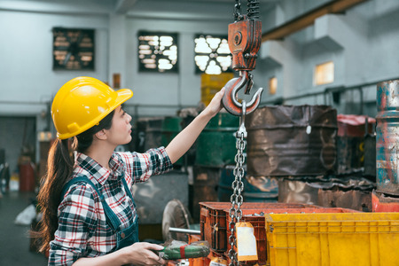 beautiful young industry factory female worker adjusting chain cranes machining when she ready to...