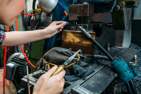 professional components factory female staff place parts in milling machine and holding pliers with selective focus photo.の写真素材