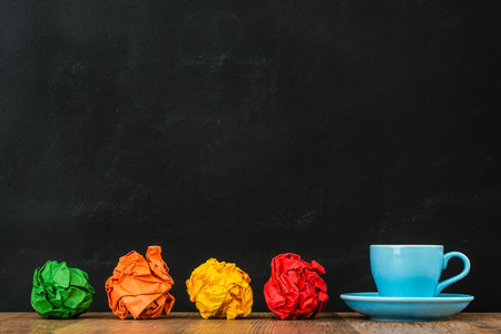 blue coffee cup with rainbow paper balls together on wood floor display design creative inspiration ideas concept on blackboard wall background.の写真素材