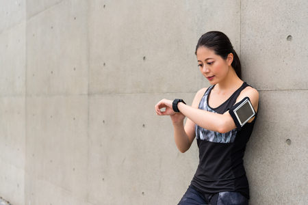 beautiful professional female athlete wearing smart watch using sports app record personal heart rate and grades ready for running training on gray background.の写真素材
