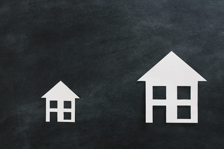 high angle view photo of estate investment advertising with two different size paper house model isolated on black chalkboard background.の写真素材