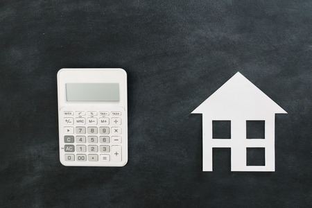 estate investment concept with calculator and paper model isolated on black chalkboard background. high angle view photo.の写真素材