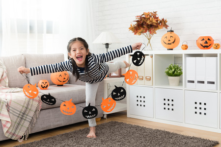 happy kid feel excited to showing the halloween paper decorations before the party in the living room at homeの写真素材