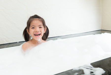 pretty female kid children playing foam water in bathroom at home.の写真素材