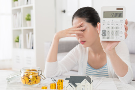 selective focus photo of pretty elegant housewife showing family negative saving number on calculator feeling upset when she planning buying new house.の写真素材