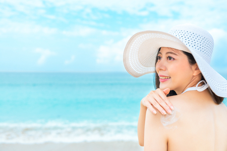 back view photo of sexy smiling girl going to sea beach vacation and coating sun protection oil resistance sunlight uv for care body skin in summer holiday.の写真素材
