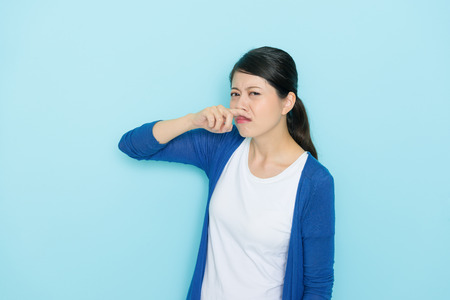 pretty attractive standing in blue background smelling unbearable odor feeling dislike and suffering.の写真素材