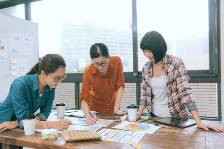 elegant attractive female designer team leader pointing color paper for colleagues and discuss new season product design.の写真素材