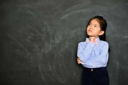 pretty cute little teacher thinking class teaching planning when she standing in front of blackboard. school education concept.の写真素材