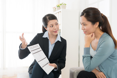 confident attractive business sales woman showing insurance case product for young girl at home and explaining scheme benefit.