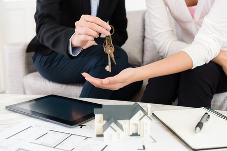 closeup photo of saleswoman giving house key for customer when buyer signing deal contract and paying full amount money.の写真素材
