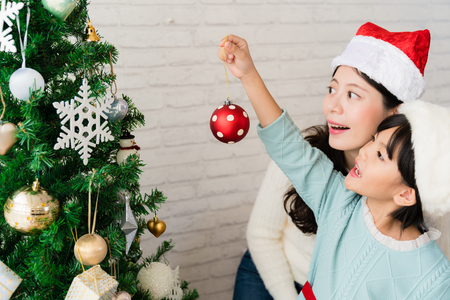 beautiful Asian mother and daughter decorating Christmas tree and having fun together.の写真素材