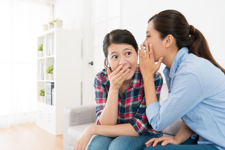 beauty young girl feeling surprised using hand cover mouth when best friend sharing secret things for her during leisure time.の写真素材