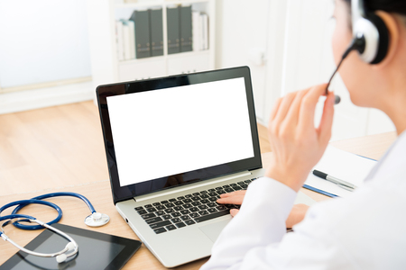 selective focus photo of female doctor wearing headphone talking with sick people and using mobile computer processed problem through online service system.の写真素材