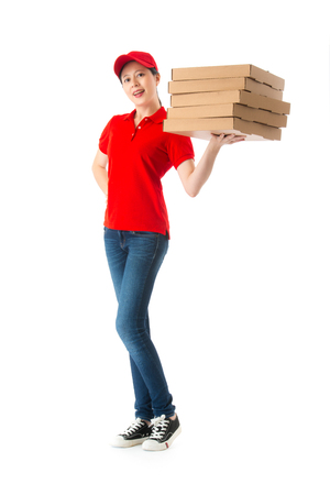 happy beautiful female pizza delivery worker standing in white background with many box and looking at camera.の写真素材