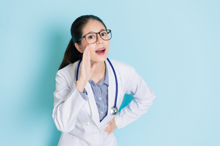 beautiful elegant woman doctor standing in blue background and having good information making talking posture looking at camera.の写真素材