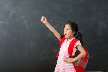 beautiful cute female kid children ready back to school isolated on blackboard background.