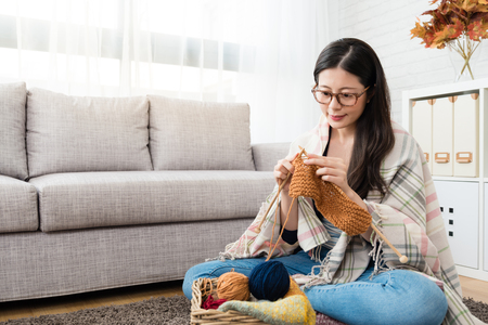 beautiful Asian women sitting on the floor of the living room and knitting for winter Christmas at homeの写真素材