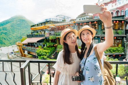 two beautiful girls taking selfie photo of famous landmarks Amei tea house of Jiufen Taiwan. Travel holiday vacation concept.の写真素材