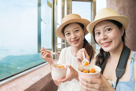 two traveler girls love the famous Taiwan local food on top of Jiufen hill of Taipei city.の写真素材