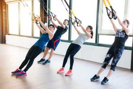 team of Asian people training with total body resistance exercises together in the sunshine...