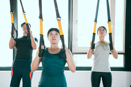 professional expert TRX pulls up and looks up together training their arms muscle with the fitness...