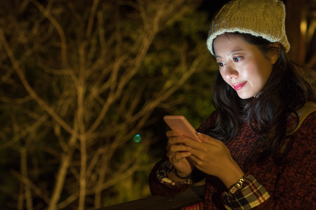 young girl texting to her friend at camping outdoor at night time.の写真素材