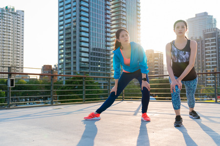 Asian female athletes stretching legs for warming up before running in the morning. Female lose weight, outdoor exercise concept.の写真素材
