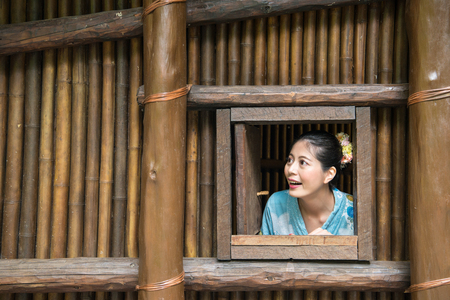 Asian woman stayed inside the bamboo made building and looking out from the window.の写真素材