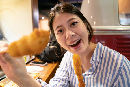 asian woman feeding japanse food to someone. in the izakaya, osaka.の写真素材