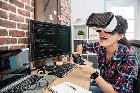 woman wearing virtual reality goggles and playing thru the game controller excitedly.の写真素材
