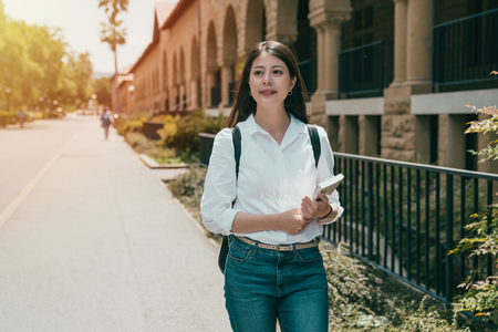 beutiaul female international student hoding her book and heading to the classroom of subject.の写真素材