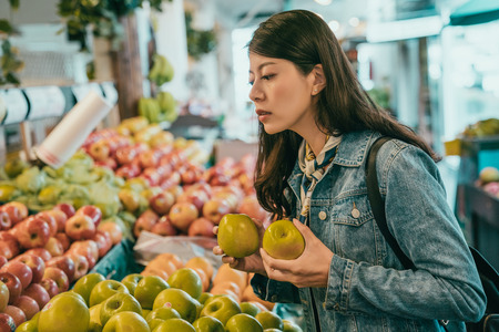 young traveler buying fruits in the original farmers market, she decided to buy those green apples and still picking the othersの写真素材