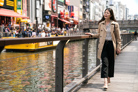 businesswoman relaxing and walking beside the river, she puts her hands on the handrailの写真素材