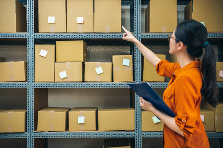 professional woman works in the delivery company is pointing to the packages which need to arrived todayの写真素材