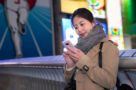 elegant female traveler sending her friends the night view photo which she just tookの写真素材